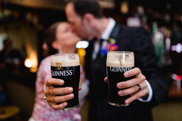 just married couple toasting and kissing with two pints of guiness